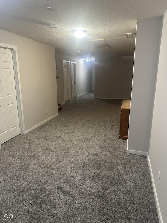 hallway with a textured ceiling, carpet flooring, and baseboards