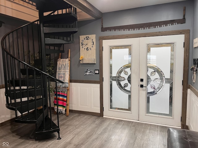 entryway with a wainscoted wall, wood finished floors, stairs, french doors, and beamed ceiling