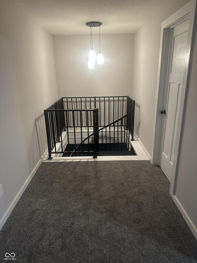 interior space with a textured ceiling, carpet, and baseboards