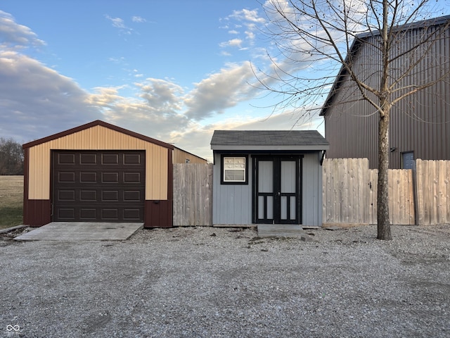 garage featuring gravel driveway and fence