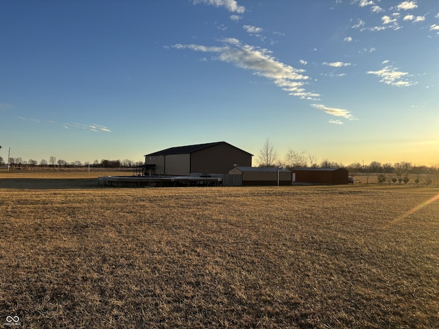 yard at dusk featuring an outdoor structure and an outbuilding