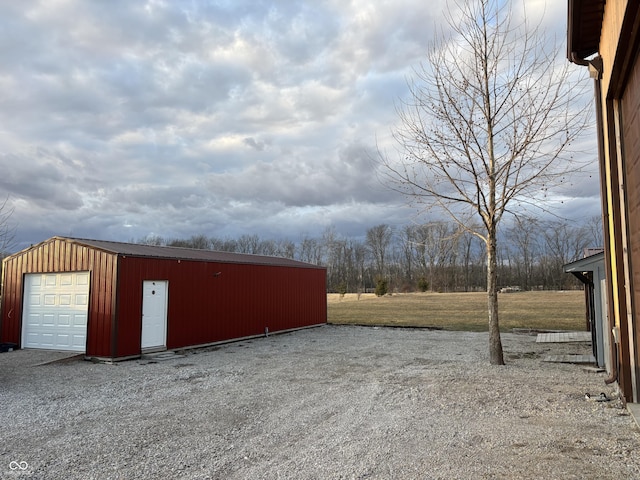 exterior space with driveway, a detached garage, and an outdoor structure