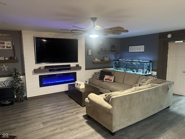 living area featuring a fireplace, a ceiling fan, and wood finished floors