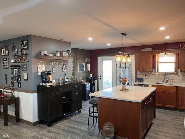 kitchen featuring wood finished floors, a sink, light countertops, backsplash, and a center island