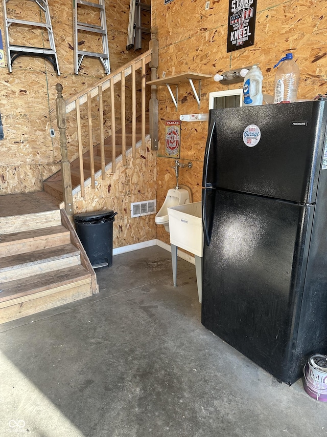 interior details with visible vents, concrete flooring, and freestanding refrigerator