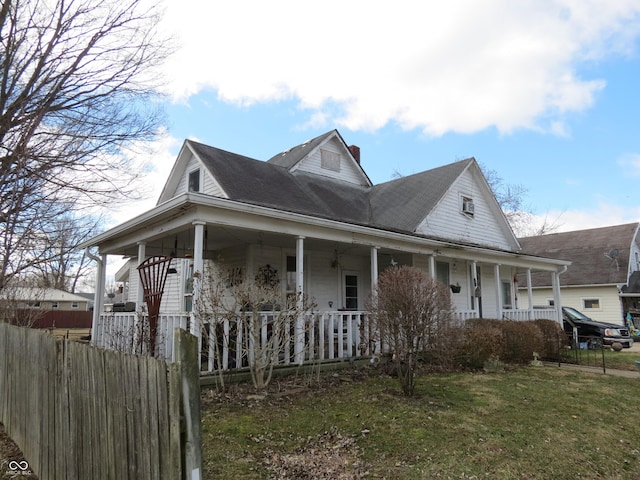 view of front of home featuring a fenced front yard, a front yard, covered porch, and a chimney