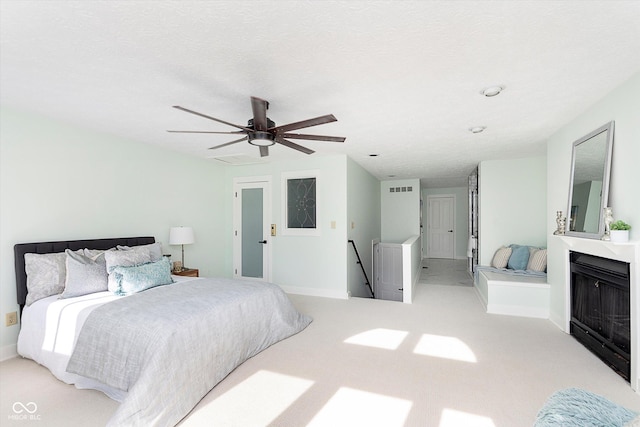 bedroom featuring ceiling fan, light carpet, a fireplace, visible vents, and baseboards