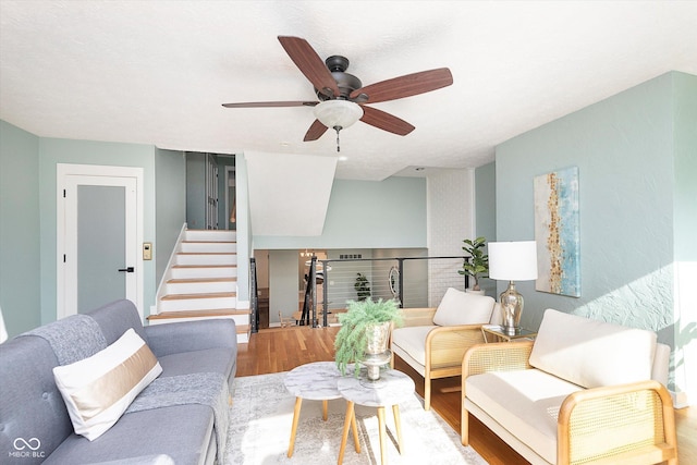 living room featuring a ceiling fan, stairway, and wood finished floors