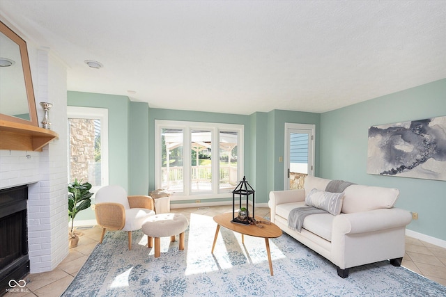 living room with a brick fireplace, baseboards, and light tile patterned floors