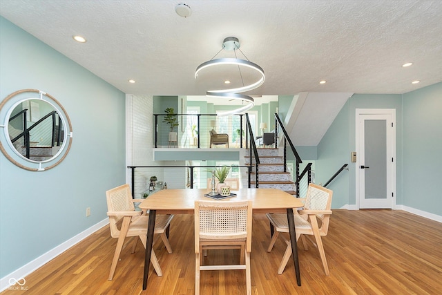 dining area with a textured ceiling, baseboards, wood finished floors, and recessed lighting