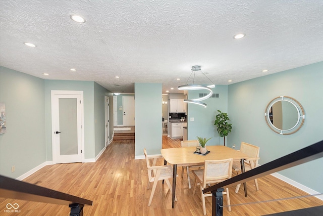 dining area featuring light wood finished floors, baseboards, and recessed lighting