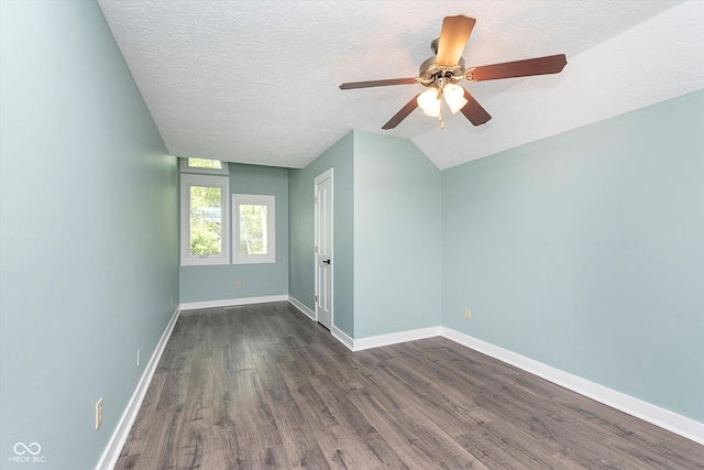 spare room featuring lofted ceiling, dark wood-type flooring, ceiling fan, a textured ceiling, and baseboards