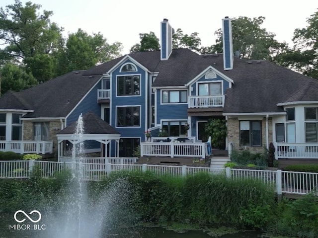 rear view of house with stone siding and fence