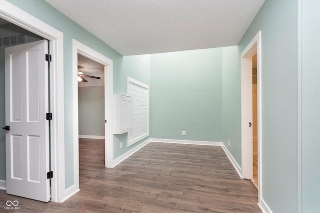 hall with baseboards, dark wood finished floors, and a textured ceiling