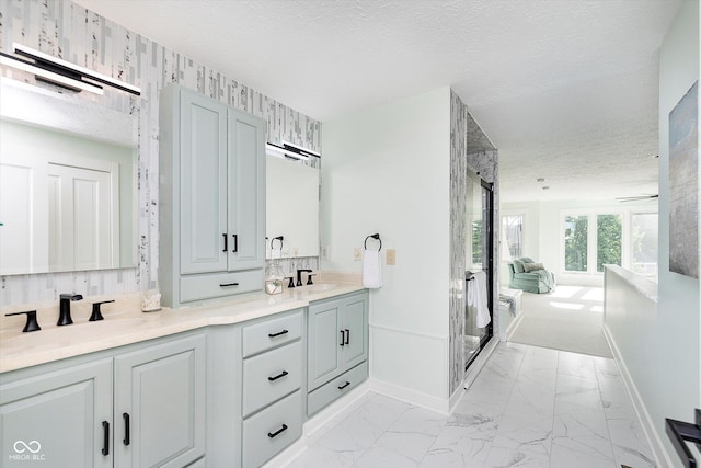 full bath with double vanity, a stall shower, baseboards, marble finish floor, and a textured ceiling