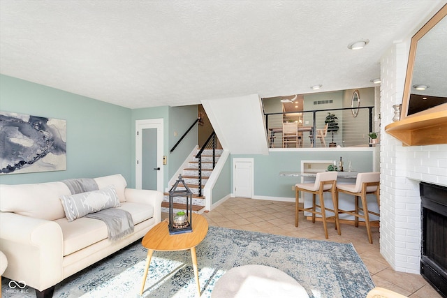 tiled living room with baseboards, a fireplace, stairway, and a textured ceiling