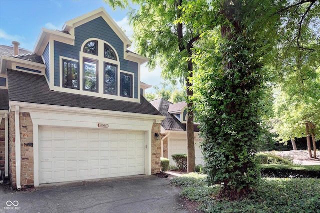 view of front of house featuring a garage, stone siding, and roof with shingles