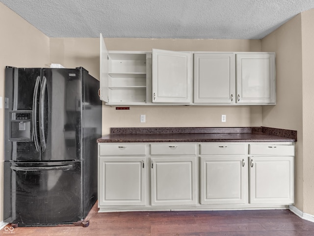 kitchen with dark wood-style floors, dark countertops, black fridge with ice dispenser, and open shelves