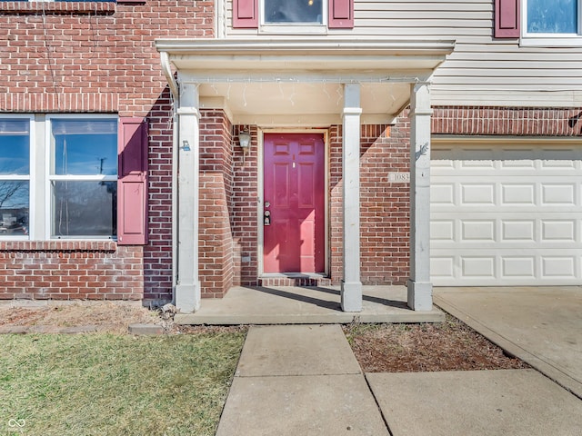 view of exterior entry featuring brick siding and an attached garage