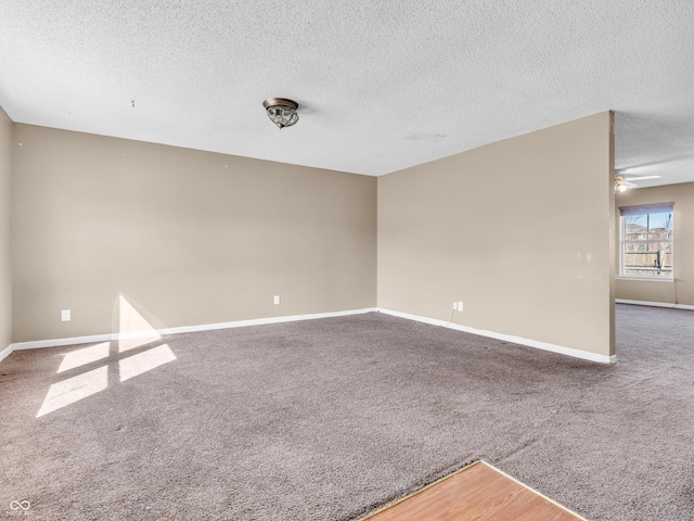 empty room featuring a ceiling fan, carpet, baseboards, and a textured ceiling