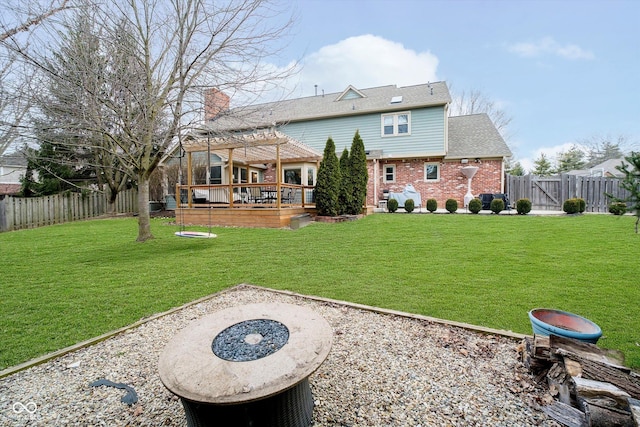 rear view of property with a fenced backyard, a pergola, a deck, a lawn, and brick siding