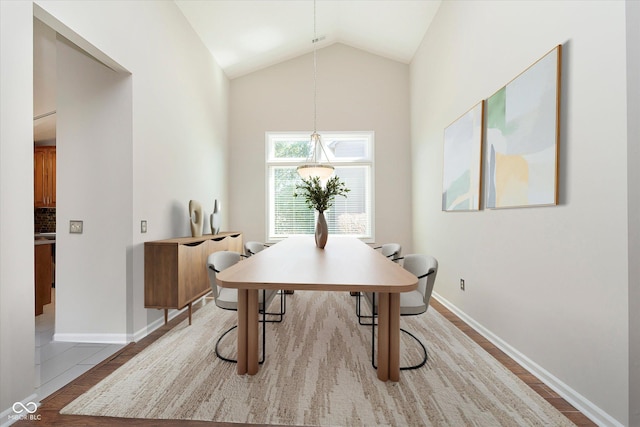 dining space with vaulted ceiling, wood finished floors, and baseboards