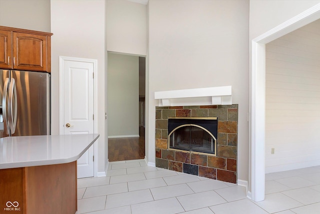 unfurnished living room with light tile patterned floors, a fireplace, baseboards, and a towering ceiling