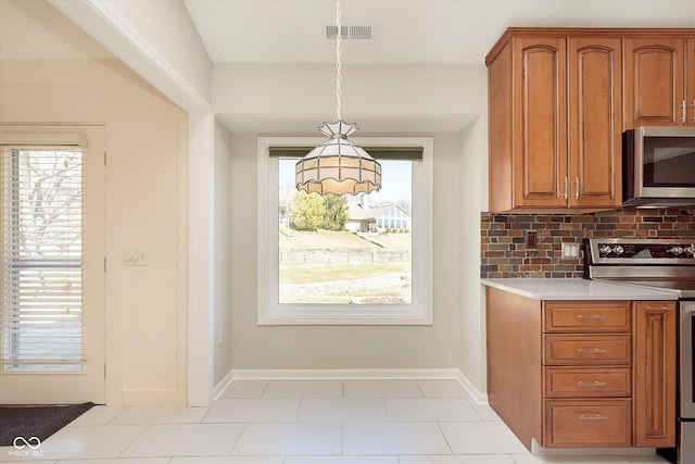 kitchen with brown cabinetry, visible vents, decorative backsplash, light countertops, and appliances with stainless steel finishes