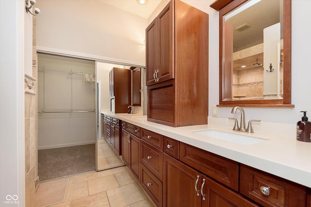 bathroom featuring double vanity, tile patterned floors, a spacious closet, and a sink