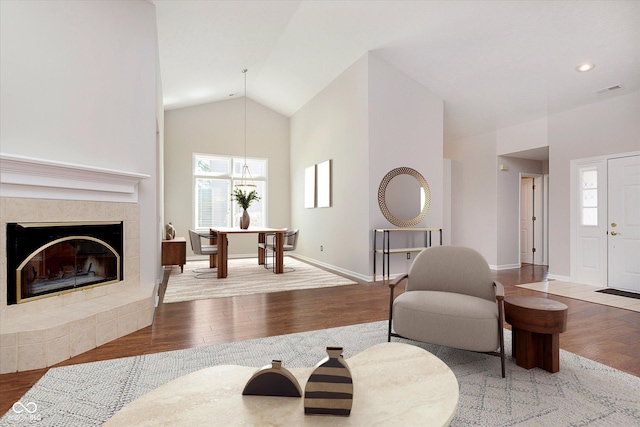 living room with wood finished floors, baseboards, high vaulted ceiling, recessed lighting, and a tile fireplace