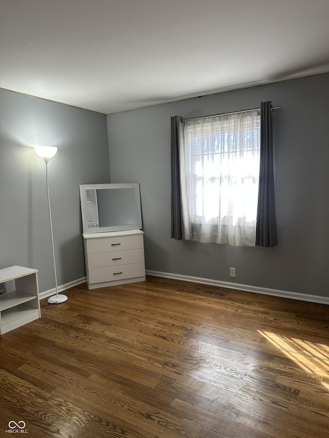 unfurnished bedroom featuring baseboards, visible vents, and dark wood-type flooring