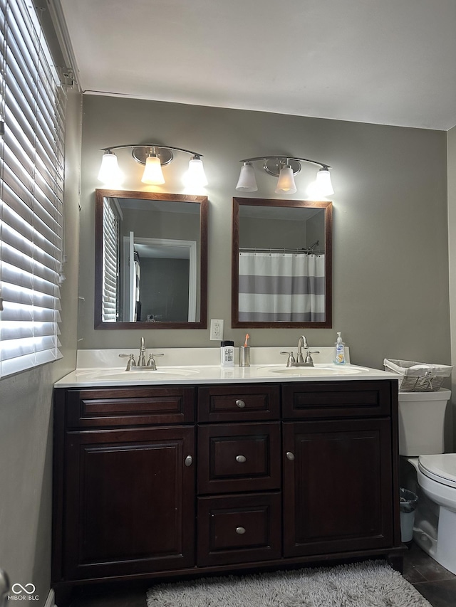 full bathroom featuring double vanity, a sink, and toilet