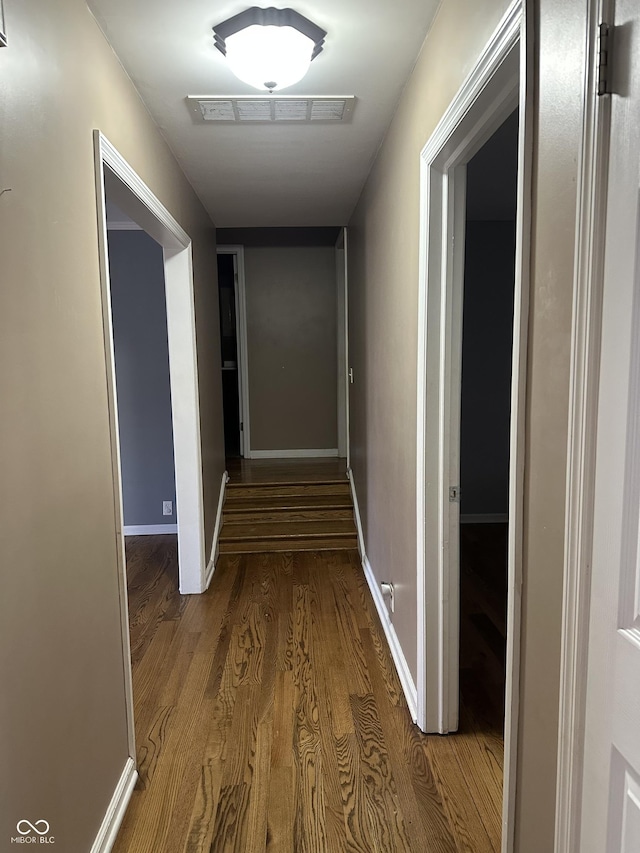 hall with wood finished floors, visible vents, and baseboards