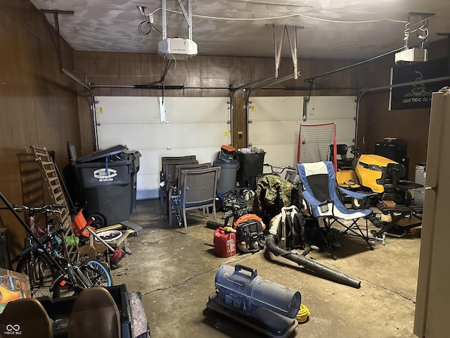 garage featuring wooden walls, freestanding refrigerator, and a garage door opener