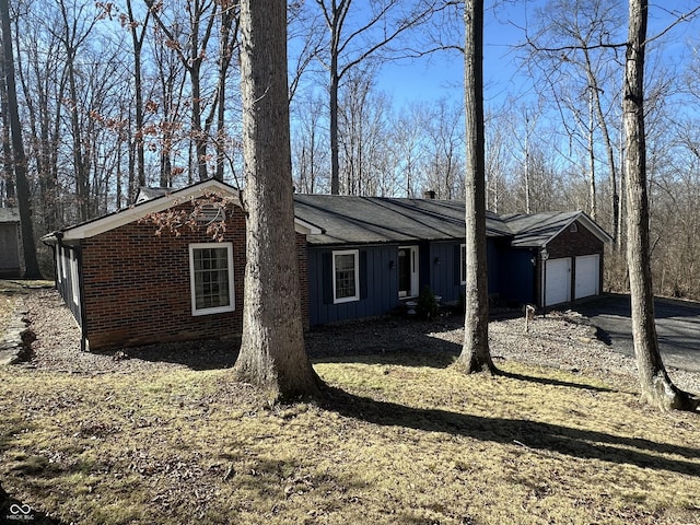 view of property exterior featuring a garage, driveway, board and batten siding, and brick siding