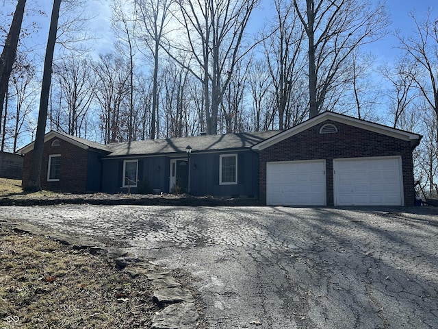 single story home featuring a garage, aphalt driveway, and brick siding