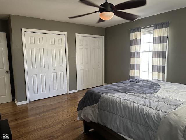 bedroom featuring ceiling fan, wood finished floors, two closets, and baseboards