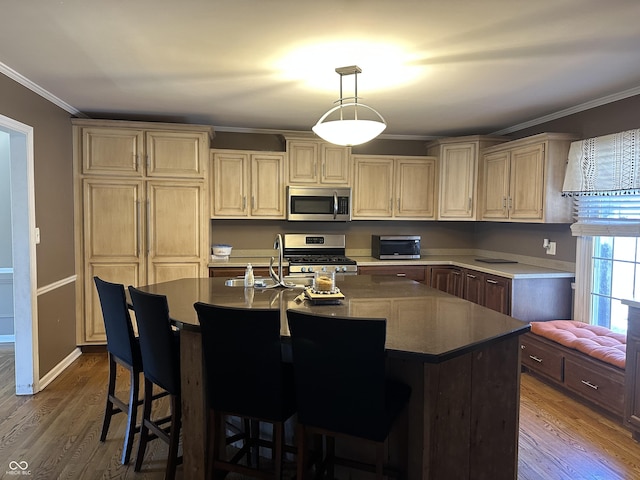 kitchen featuring dark wood-style flooring, a sink, ornamental molding, appliances with stainless steel finishes, and a center island with sink