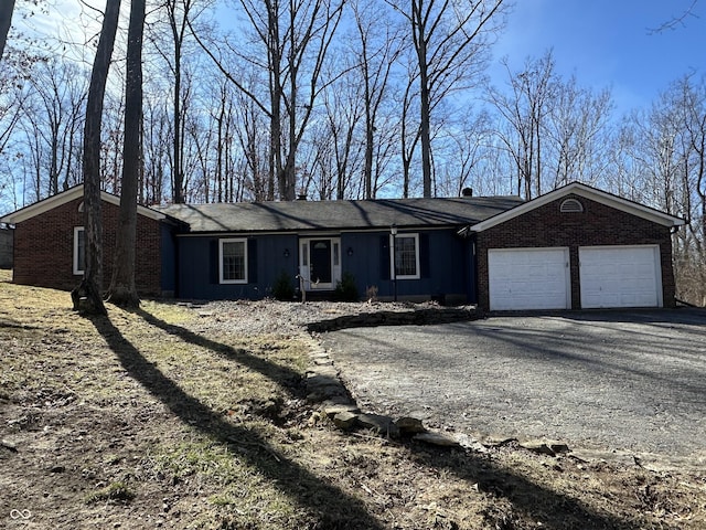 ranch-style home featuring driveway, brick siding, and an attached garage