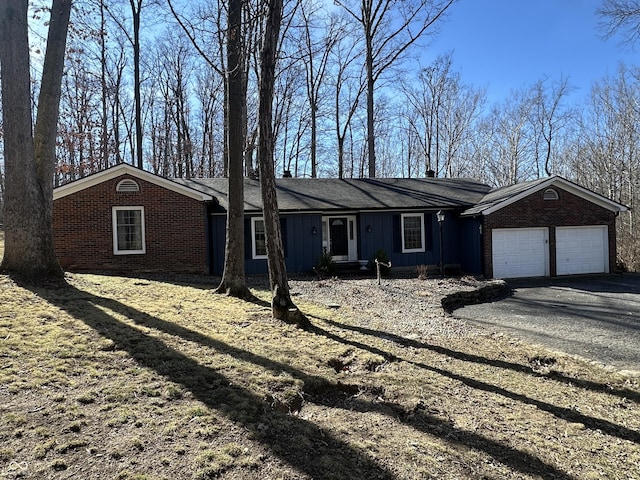 ranch-style house featuring an attached garage, aphalt driveway, board and batten siding, and brick siding