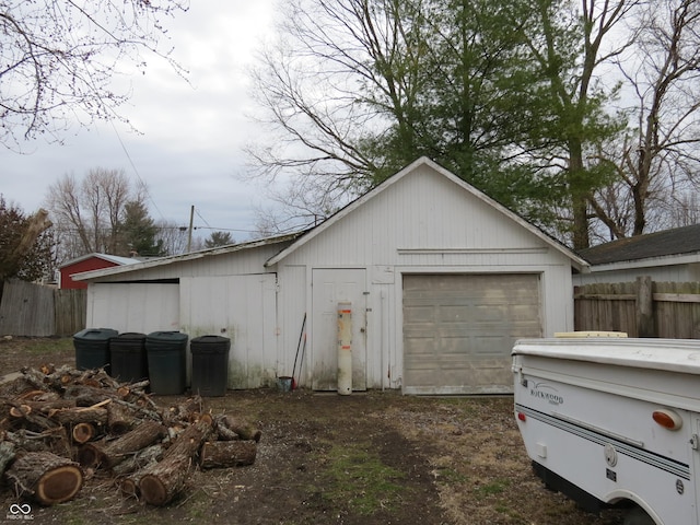 detached garage featuring fence and dirt driveway