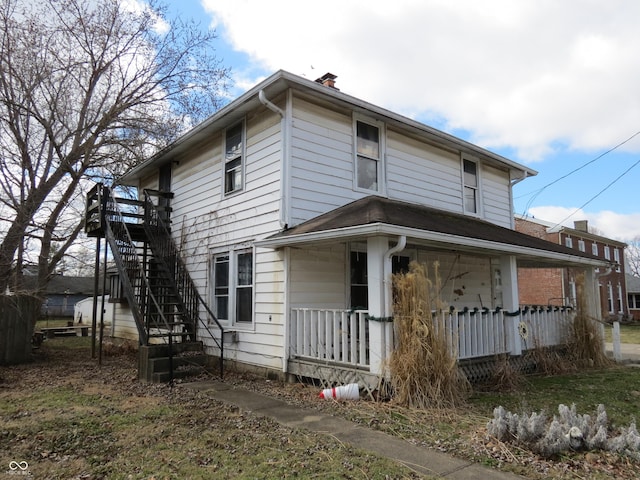 view of front of house with a chimney, covered porch, and stairway