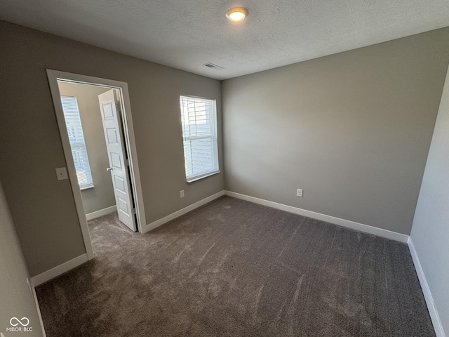 unfurnished bedroom featuring a textured ceiling, carpet flooring, visible vents, and baseboards