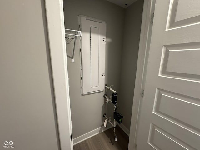 laundry room featuring wood finished floors, electric panel, and baseboards