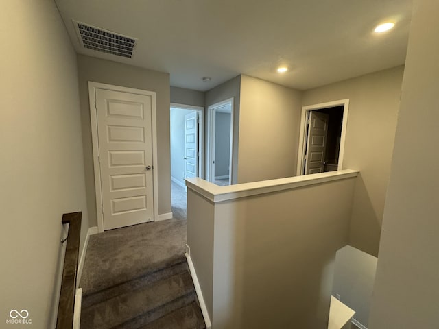 hallway featuring recessed lighting, an upstairs landing, visible vents, baseboards, and dark colored carpet