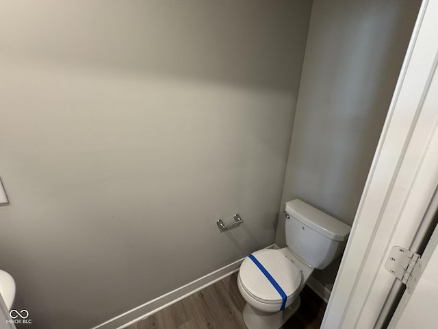 bathroom with baseboards, toilet, and wood finished floors