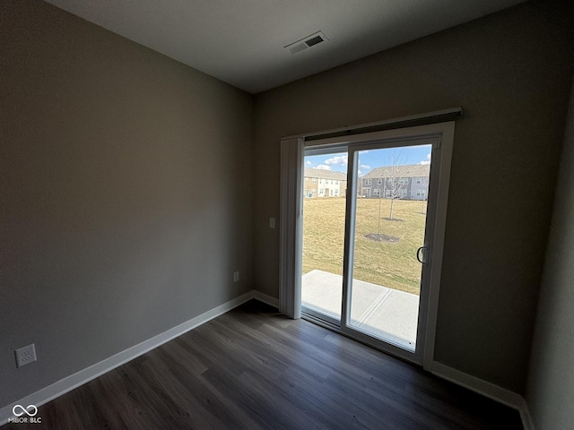 empty room with baseboards, visible vents, and dark wood-type flooring