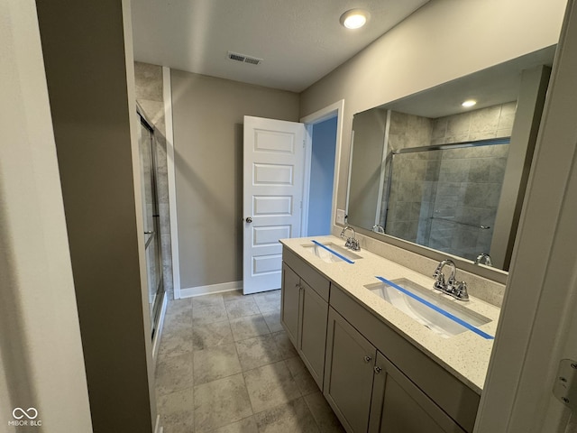 bathroom with double vanity, a stall shower, a sink, and visible vents