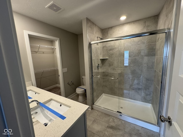 full bathroom featuring toilet, a stall shower, vanity, and visible vents