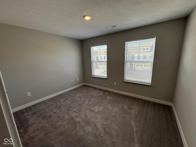 spare room with a textured ceiling, carpet floors, visible vents, and baseboards